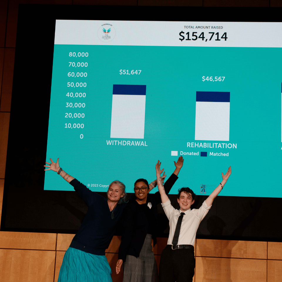 Three smiling speakers from the Connect for Youth event in front of a screen reading '$154,714'
