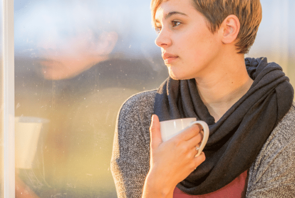 Young woman holding a cup of tea and staring out of a window