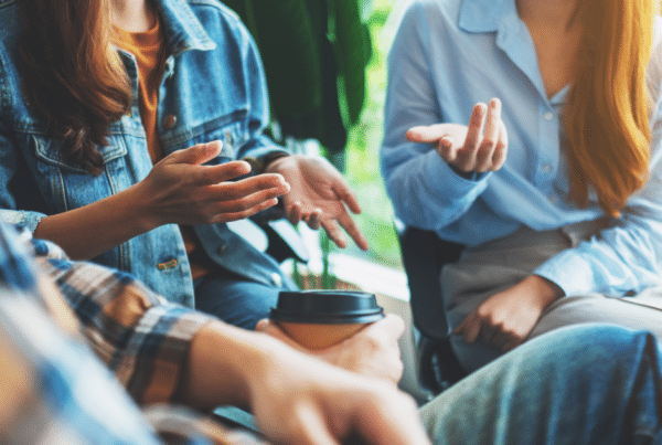 young people talking in a circle. The focus is on their hands