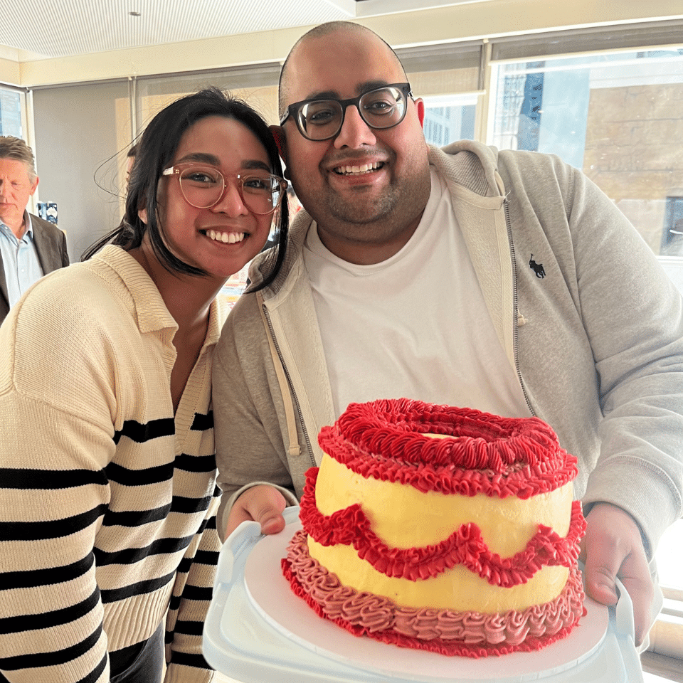 Two InfoTrack employees smiling and holding a cake