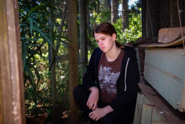 young woman sitting outside, looking downcast