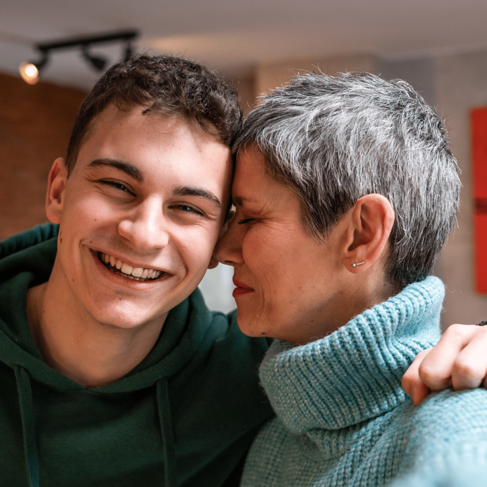 Mother hugs her smiling teenage son