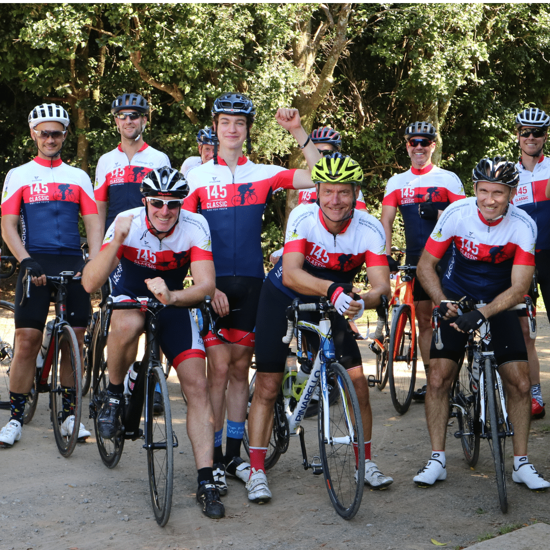 A group of men on bikes wearing cycling gear and helmets, smiling