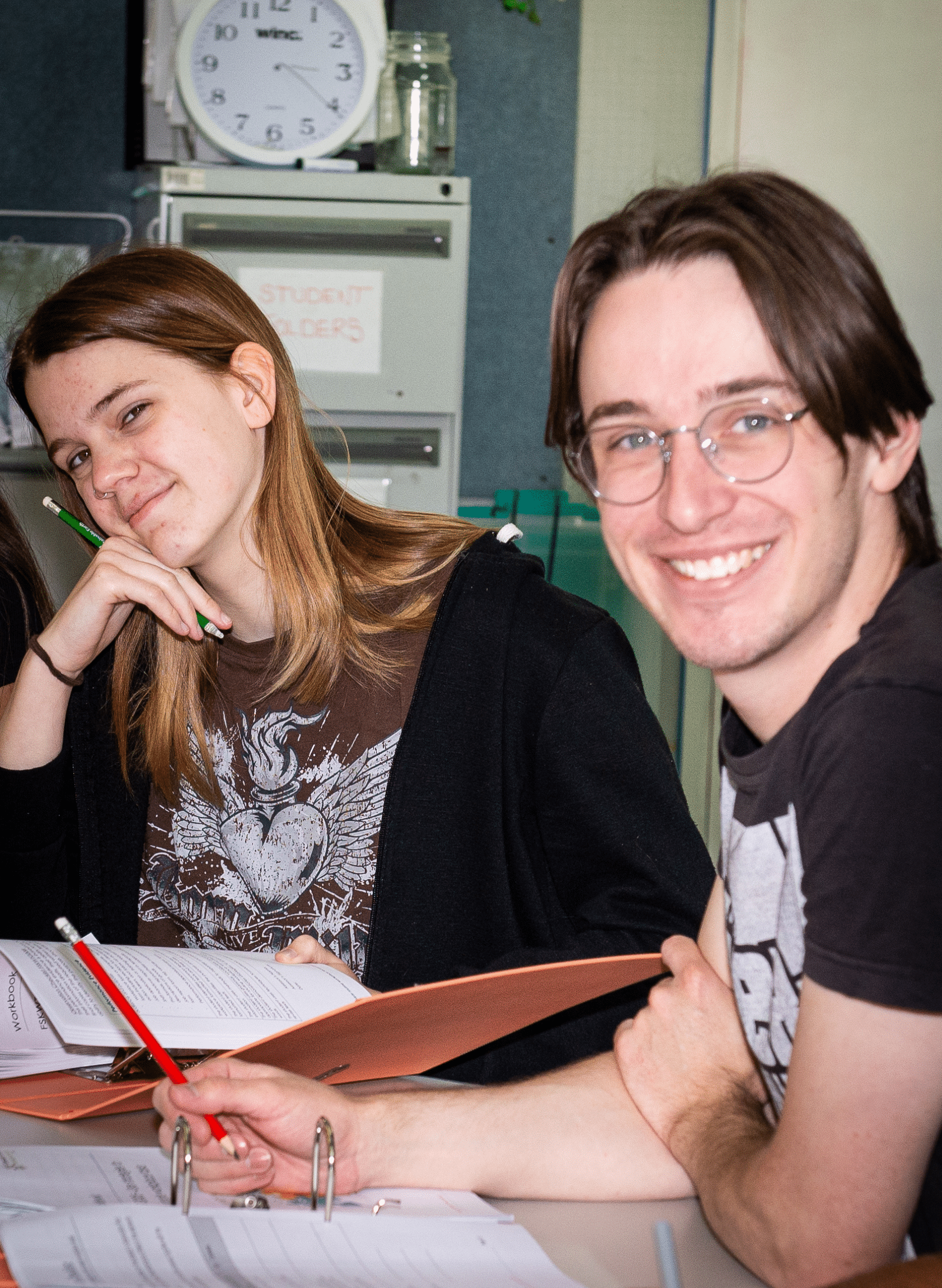 two young people studying at desks and smiling