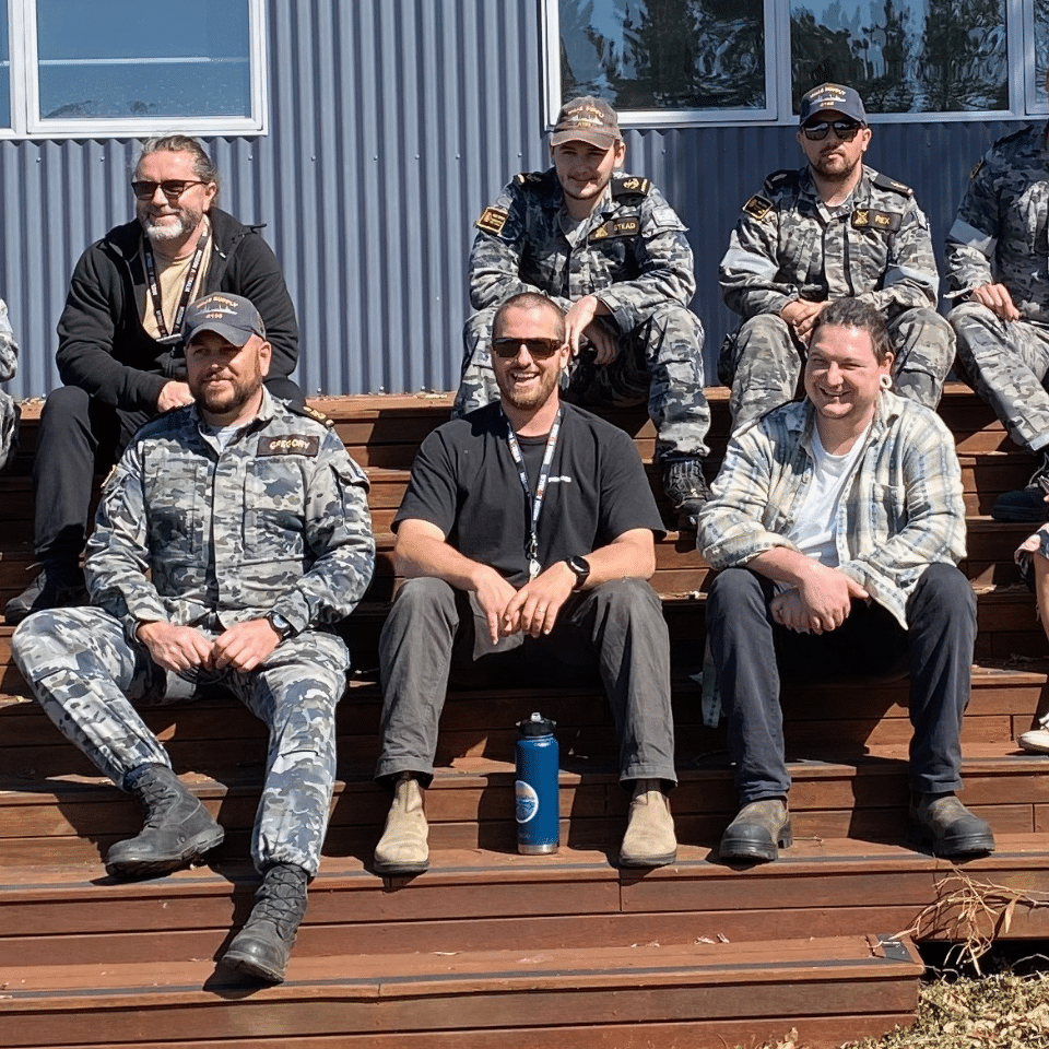 Crew of the HMAS Supply sitting on the steps of the patio at Triple Care Farm