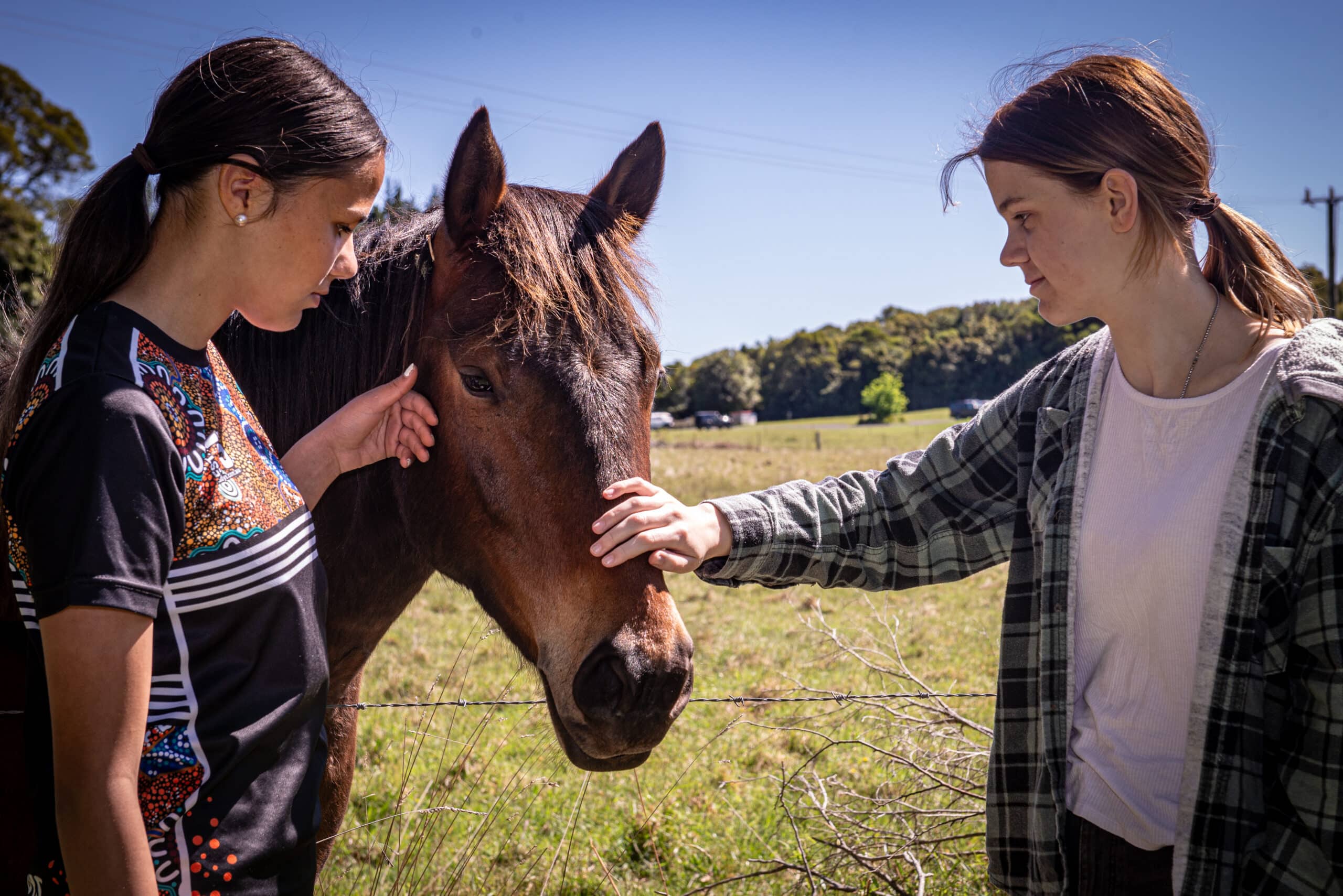 two young women patting a horse at Triple Care Farm