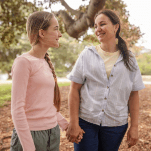 Young woman and older woman walk hand in hand outside