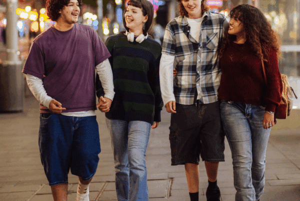Four happy teens walk through the city at night.